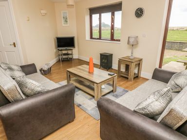 A living room with two sofas a coffee table a small television and a side table with a lamp at Shoreline in Marazion