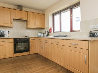 A kitchen with wooden cabinets a built in oven a microwave toaster kettle and a radio at Shoreline in Marazion