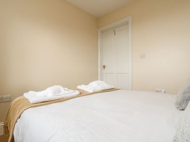 A bedroom with a bed covered with white sheets and towels on a blanket near a closed door at Shoreline in Marazion