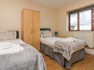 A bedroom with two single beds a wooden wardrobe and a window at Shoreline in Marazion