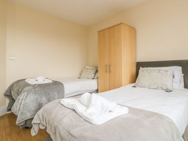 A bedroom with two single beds and a wooden wardrobe between them at Shoreline in Marazion