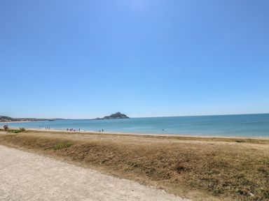 A beach with people near the shore and an island in the sea at Shoreline in Marazion