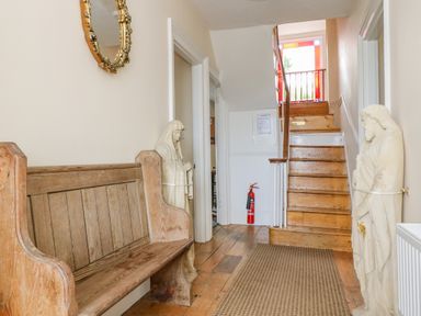 A hallway with a wooden bench statues on either side stairs at 1 Dormer Villas in Portscatho