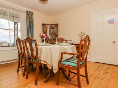 A dining room with a table set with plates and glasses surrounded by wooden chairs at 1 Dormer Villas Portscatho