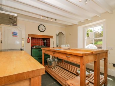 A kitchen with wooden countertops an island and a green stove at 1 Dormer Villas in Portscatho