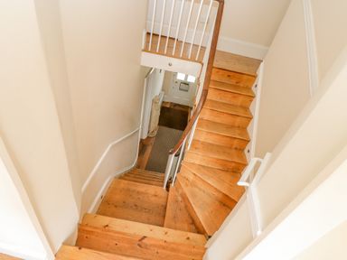 A wooden staircase with white railings inside a house at 1 Dormer Villas in Portscatho