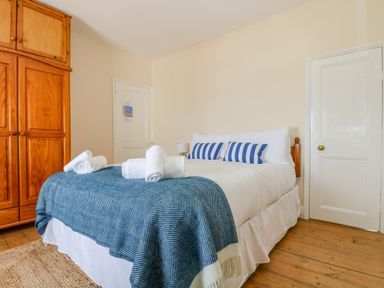 A bedroom with a double bed with blue striped pillows and white towels on a blue blanket at 1 Dormer Villas in Portscatho