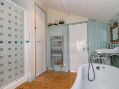 A bathroom with clawfoot bathtub sink shower and wooden floor at 1 Dormer Villas in Portscatho