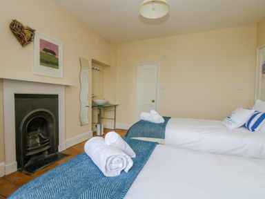 A bedroom with two single beds a fireplace and a washbasin at 1 Dormer Villas in Portscatho