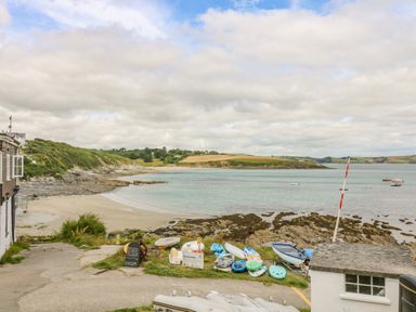 A coastal area with kayaks and boats near a beach surrounded by hills and water at 1 Dormer Villas in Portscatho
