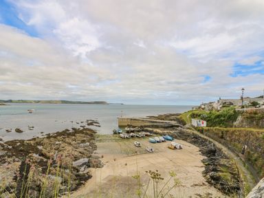 A small harbor with boats on a sandy shore and rocky edges with houses on the right at 1 Dormer Villas in Portscatho