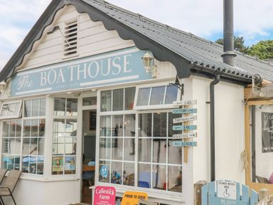 Exterior of The Boathouse licensed cafe with a signpost showing directions for cafe ice cream takeaway bar fish and chips and beach at 1 Dormer Villas in Portscatho