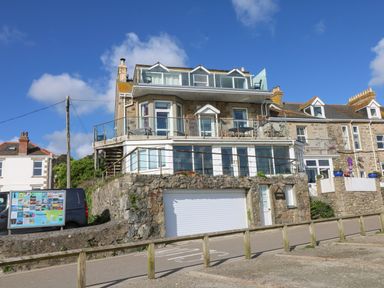 A multi-story stone house with glass balconies and a garage door at Mount View in Marazion
