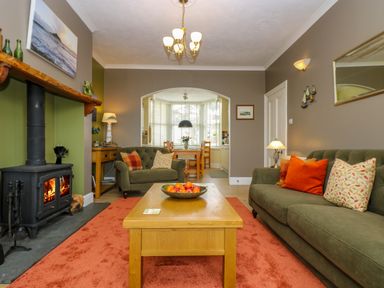 A living room with green sofas orange cushions and a fireplace at Mount View in Marazion