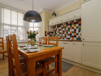A kitchen with a wooden dining table set with plates and glasses and colorful tiled backsplash at Mount View in Marazion