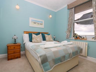 A bedroom with a double bed two bedside tables with lamps a large window with curtains and a view at Mount View in Marazion