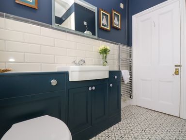 A bathroom with a white sink and blue cabinets a towel rail and a white door at Mount View Marazion