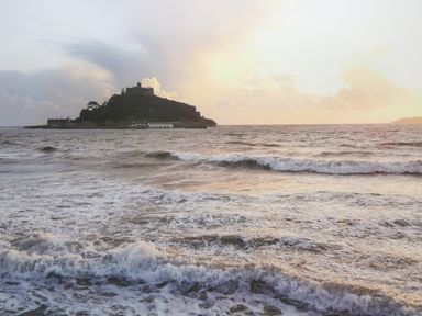 A view of an island with buildings and a castle surrounded by the sea at Mount View in Marazion