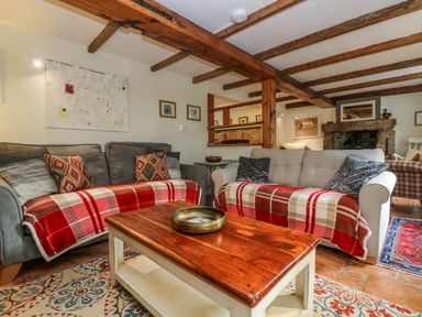 A living room with two sofas covered with red plaid throws and a wooden coffee table at Chenalls Cottage in Helston