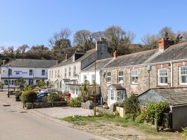A street view with stone and brick houses and a building with piskey cove b b sign at Mallards in Pentewan