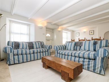 A living room with two striped sofas and a wooden coffee table at Mallards in Pentewan