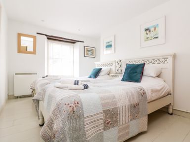 A bedroom with two single beds with patchwork quilts and blue pillows at Mallards in Pentewan