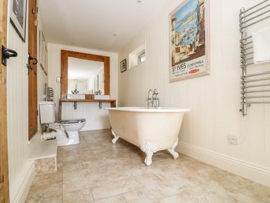 A bathroom with a clawfoot bathtub a double sink and a toilet at Mallards in Pentewan