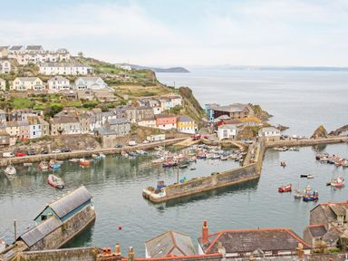 A coastal village with houses on a hillside a harbor with boats and a stone pier at Mallards in Pentewan