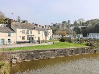 A riverside scene with a pub building called The Ship Inn and surrounding houses at Mallards in Pentewan