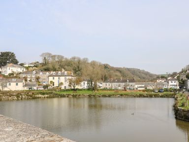 A body of water with houses and trees in the background at Mallards in Pentewan
