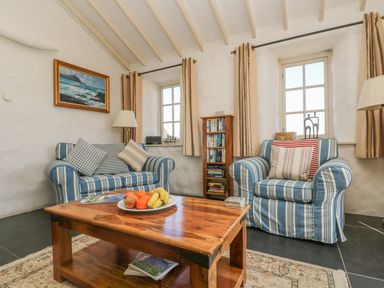 A sitting room with striped armchairs and a wooden coffee table at Boar's House in Penzance