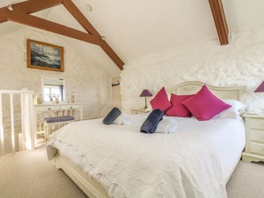 A bedroom with a bed with pink pillows and rolled towels on a bed at Boar's House in Penzance