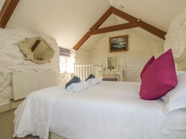 A bedroom with a white bed and magenta pillows a mirror on the wall and a vanity table at Boar's House in Penzance