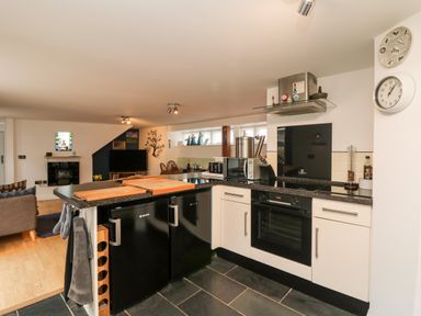 A kitchen with black and white cabinetry and appliances including an oven microwave and refrigerator at Ebenezer Cottage in Marazion