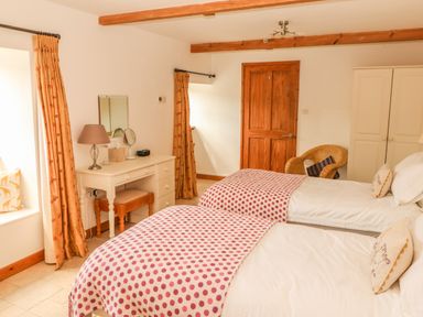 A bedroom with two single beds a dressing table a chair and a wardrobe at Back Of Beyond in St Ives