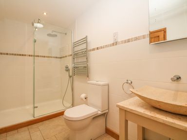 A bathroom with a glass shower enclosure toilet and stone sink at Back Of Beyond in St Ives