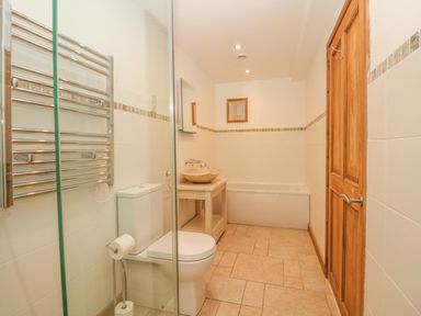 A bathroom with a toilet a bathtub a sink with a mirror and a wooden door at Back Of Beyond in St Ives