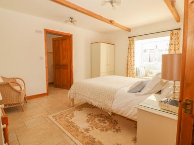 A bedroom with a bed a wardrobe a chair and a window seat at Back Of Beyond in St Ives