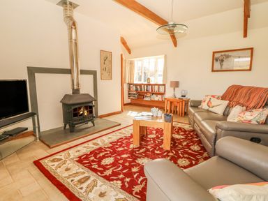 A living room with a stove fireplace sofa armchair coffee table and bookshelf at Back Of Beyond in St Ives