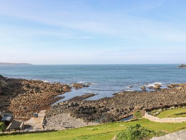 A rocky coastline with a small concrete ramp and buildings near the ocean at Back Of Beyond in St Ives