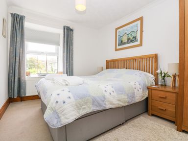 A bedroom with a bed and bedside table with lamp and flowers at Angarrack Farmhouse in Hayle
