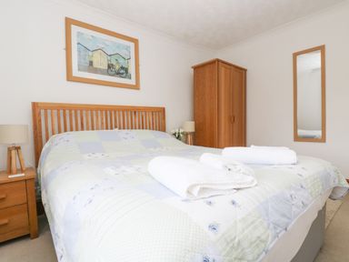 A bedroom with a double bed and wooden furniture including a wardrobe and bedside tables at Angarrack Farmhouse in Hayle