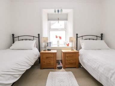 A bedroom with two single beds and wooden nightstands by a window at Angarrack Farmhouse in Hayle