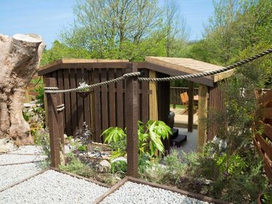 A garden area with wooden fencing and a small deck with chairs and table at Godrevy Cottage in Hayle
