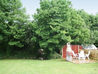 A garden area with lawn trees a red shed barbecue and white patio chairs at Godrevy Cottage in Hayle