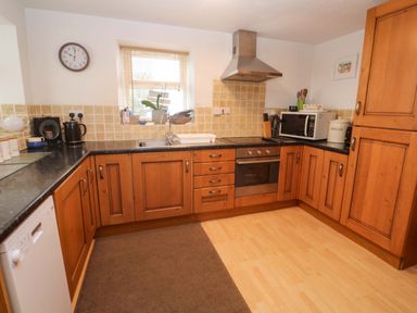 A kitchen with a sink, oven, and microwave at Godrevy Cottage in Hayle