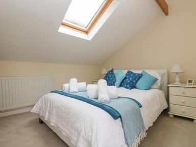 A bedroom with a double bed blue pillows and folded towels under a skylight window at Little Hamlin in Rilla Mill Nr Callington