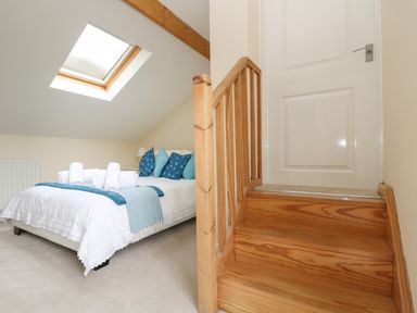 A bedroom with a bed and pillows under a skylight window next to wooden stairs and a closed door at Little Hamlin in Rilla Mill Nr Callington