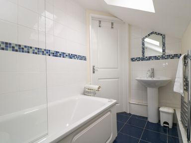 A bathroom with a bathtub a pedestal sink a mirror and a towel rail at Little Hamlin in Rilla Mill Nr Callington