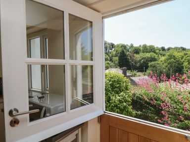 An open door showing a view of trees and pink flowers at Little Hamlin in Rilla Mill Nr Callington